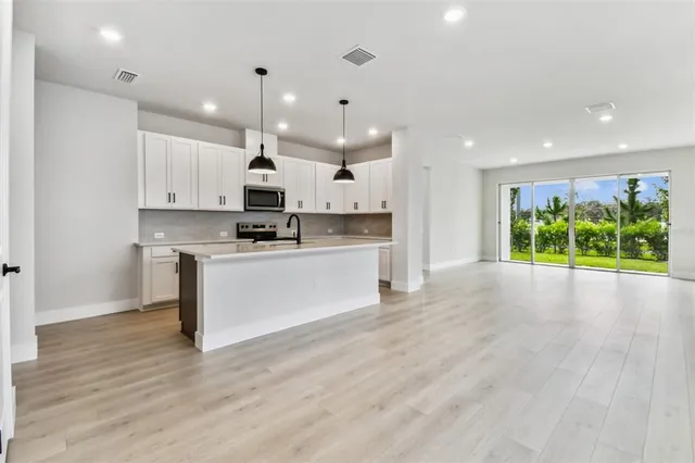 a kitchen with a stove a sink a center island and wooden floor