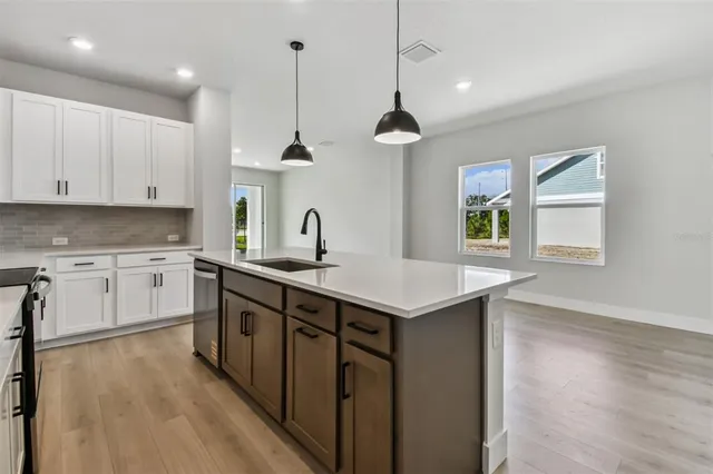 a kitchen with stainless steel appliances a sink a stove a refrigerator and island with wooden floor