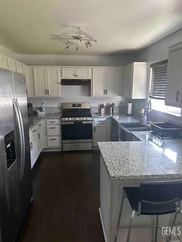 a kitchen with stainless steel appliances granite countertop a sink stove refrigerator and microwave