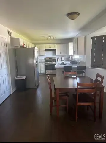 a dining room with stainless steel appliances a table and chairs