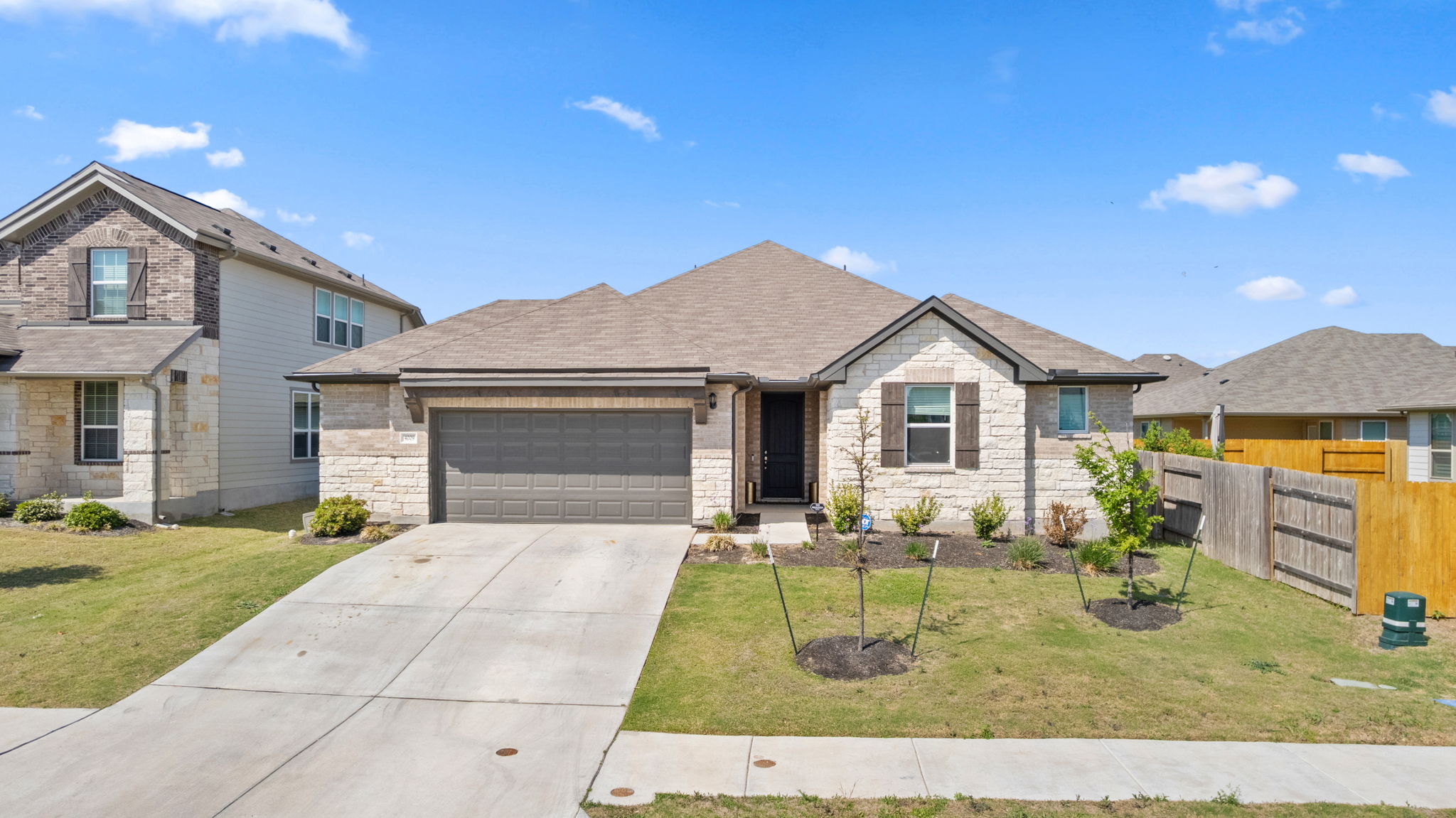 4009 Milano River Road Hutto, TX 78634 - Photo 2 of 39 View of front of property featuring a garage, driveway, stone siding, and roof with shingles