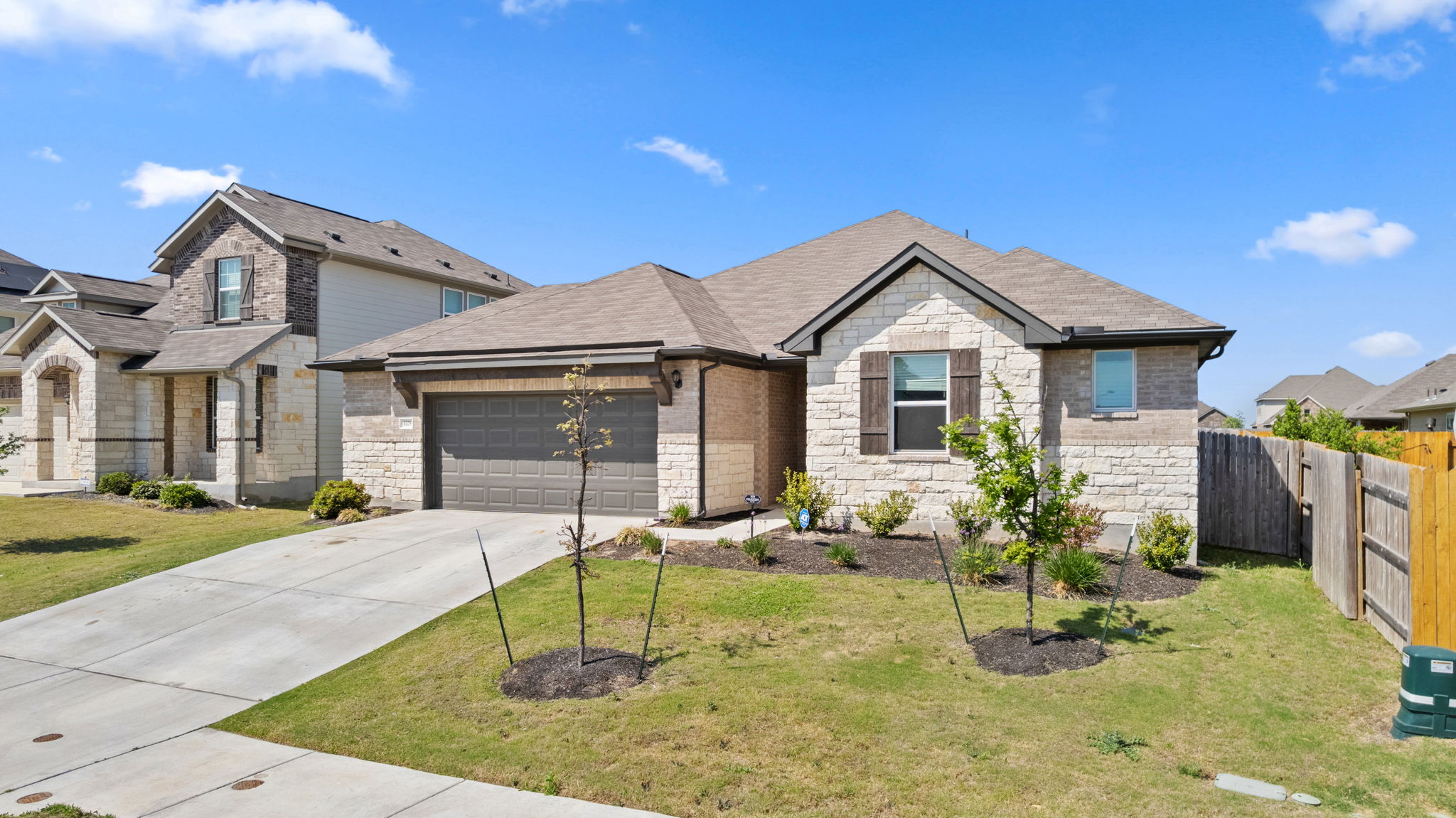 4009 Milano River Road Hutto, TX 78634 - Photo 4 of 39 View of front of house featuring a garage, concrete driveway, stone siding, and a shingled roof