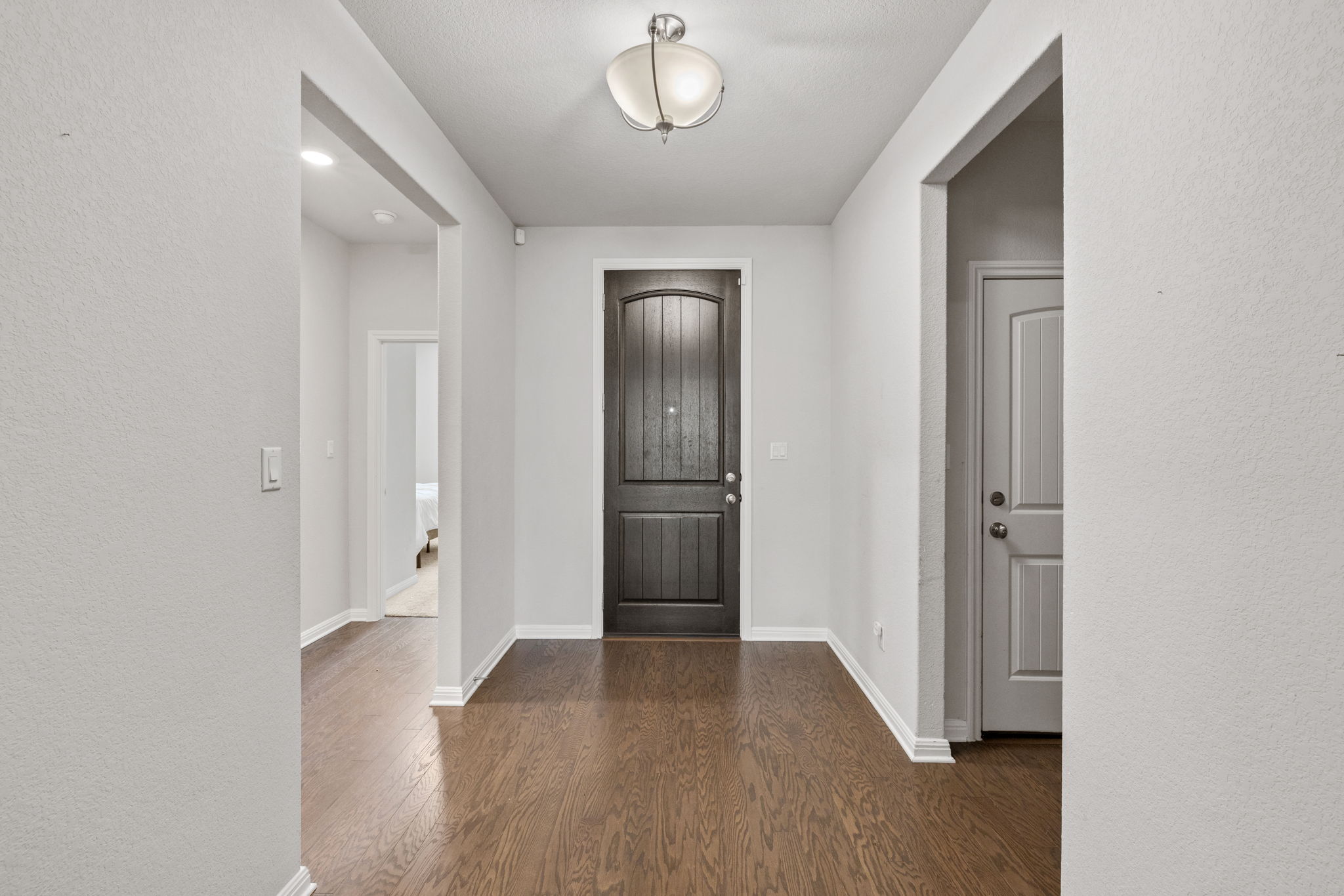 4009 Milano River Road Hutto, TX 78634 - Photo 6 of 39 Entryway with a textured wall and dark wood-style floors