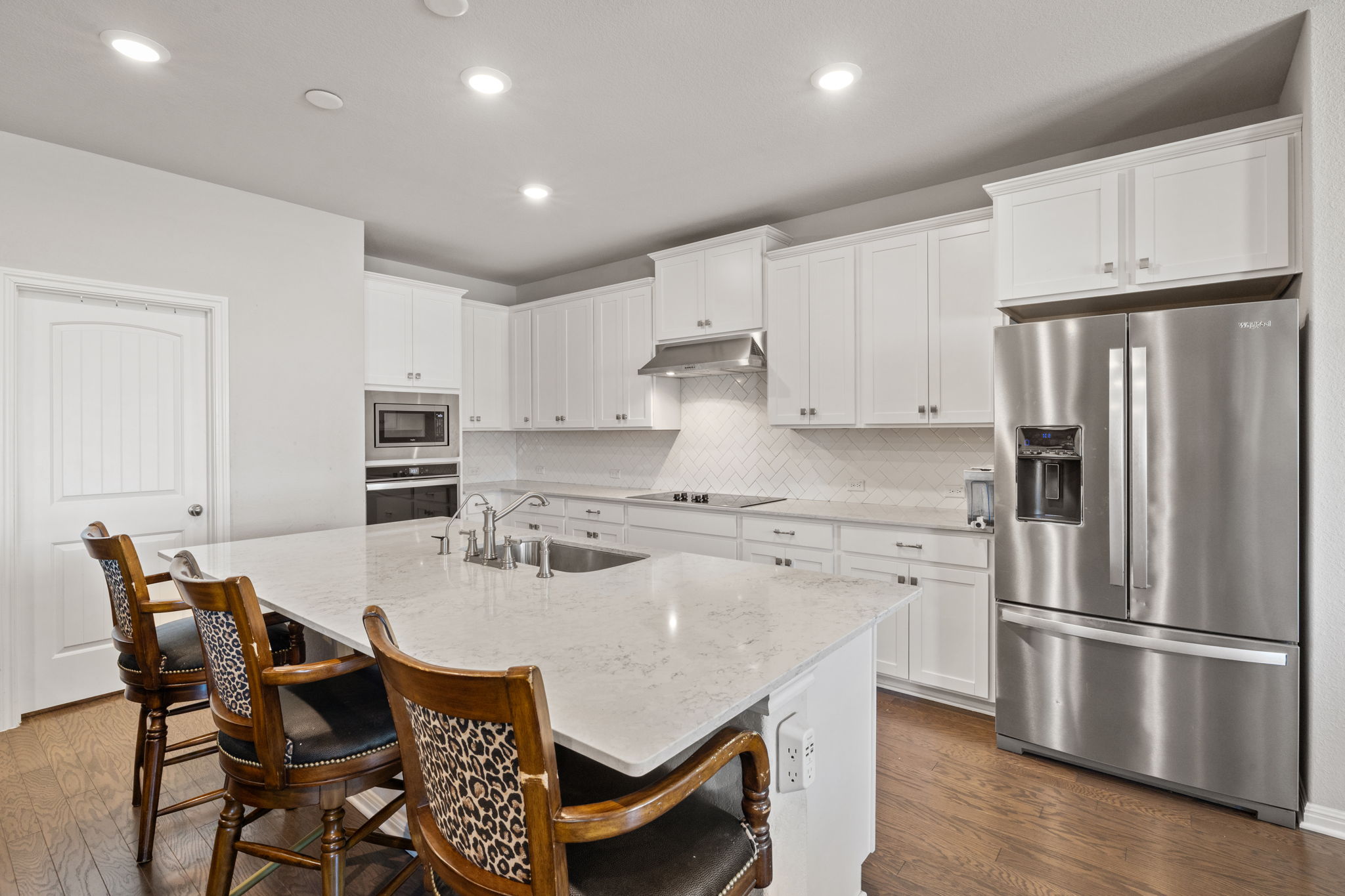 4009 Milano River Road Hutto, TX 78634 - Photo 8 of 39 Kitchen with stainless steel appliances, light stone countertops, white cabinetry, dark wood-type flooring, and recessed lighting