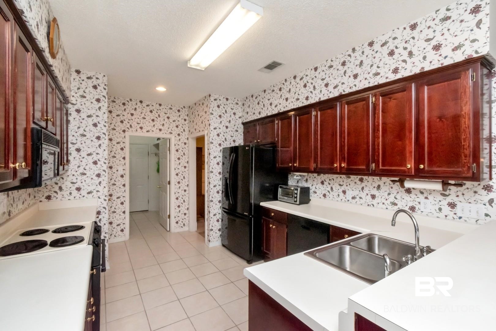 1032 Cross Gates Place Mobile, AL 36609 - Photo 13 of 34 Kitchen with black appliances, light countertops, light tile patterned floors, a textured ceiling, and bold wood finish cabinets