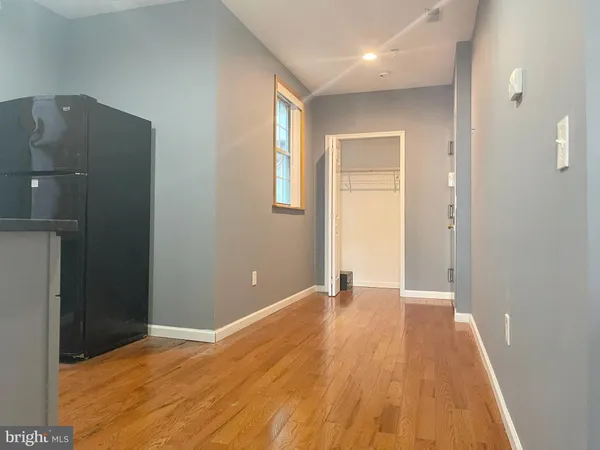 a view of an empty room with wooden floor and a bathroom