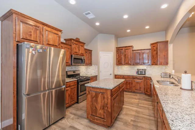 a kitchen with stainless steel appliances granite countertop a stove a sink and a microwave