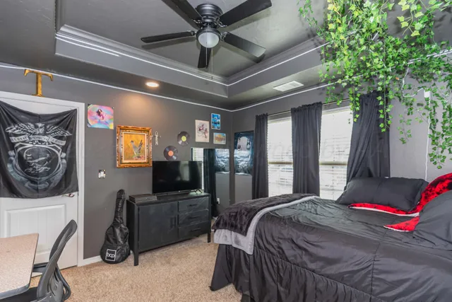 a bedroom with a bed ceiling fan and a large window
