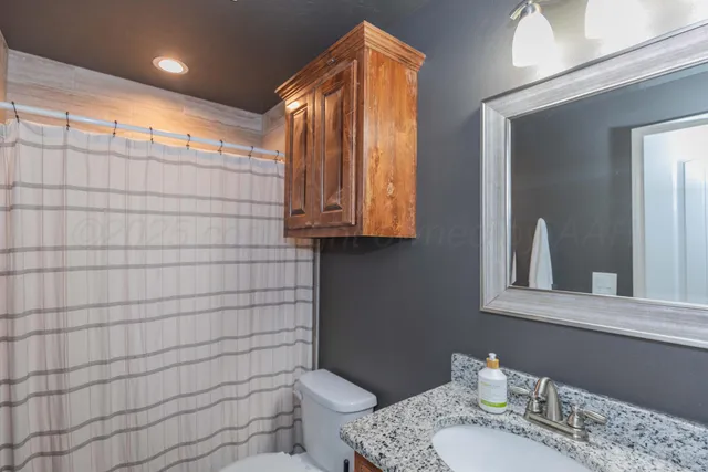 a bathroom with a granite countertop sink toilet and shower
