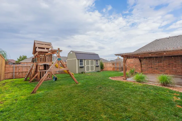 a backyard of a house with wooden fence and large trees