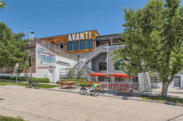 a front view of a building with lots of trees and plants