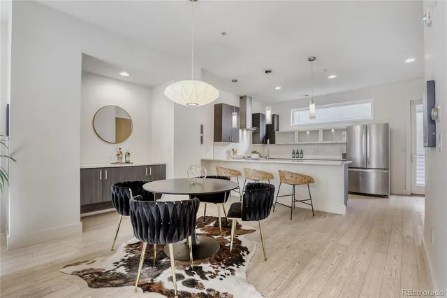 a dining room with stainless steel appliances kitchen island a table chairs and a refrigerator