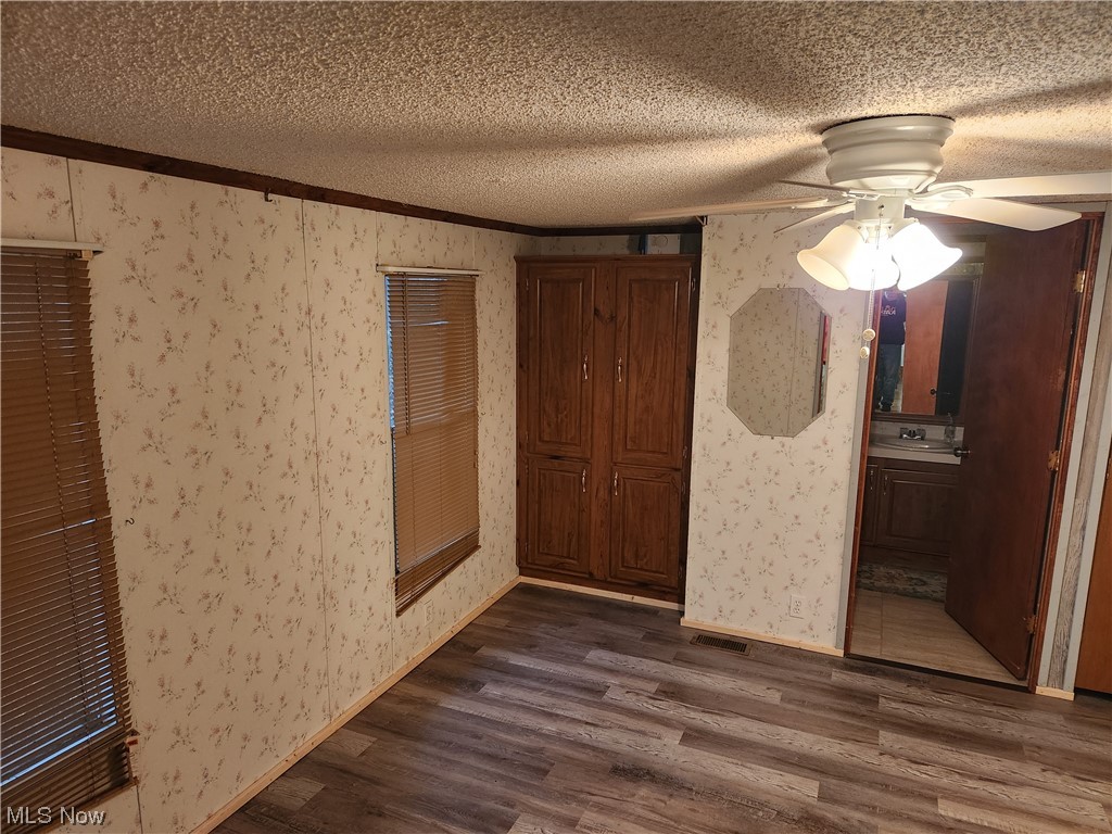 3895 Middletown Road East Youngstown, OH 44514 - Photo 18 of 28 Unfurnished bedroom with ensuite bath, ceiling fan, a textured ceiling, and dark hardwood / wood-style flooring