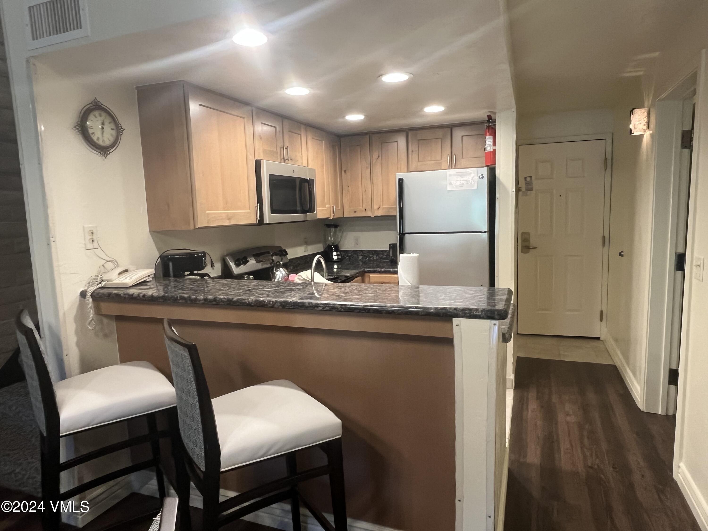 1020 Vail View Drive, Unit 340846 Vail, CO 81657 - Photo 2 of 25 a kitchen with kitchen island granite countertop a sink cabinets and wooden floor