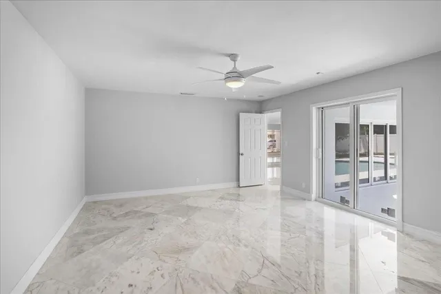 an empty room with chandelier fan and windows