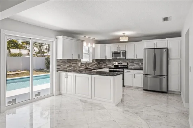 a kitchen with granite countertop a refrigerator sink and cabinets