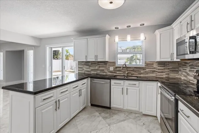 a kitchen with granite countertop white cabinets white appliances with a sink and dishwasher