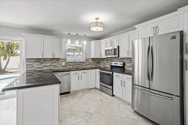 a kitchen with granite countertop a refrigerator stove top oven and sink