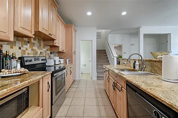 a large kitchen with stainless steel appliances granite countertop a stove a sink and a refrigerator