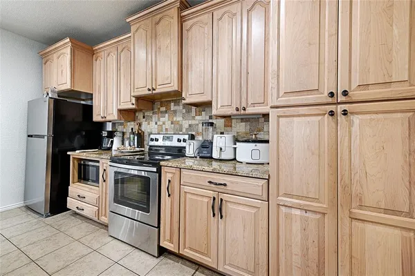 a kitchen with stainless steel appliances granite countertop white cabinets and a refrigerator