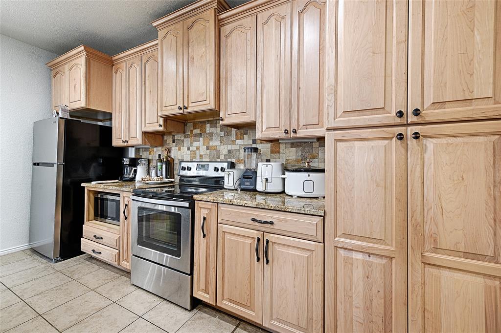 5984 Stone Mountain Road The Colony, TX 75056 - Photo 6 of 25 a kitchen with stainless steel appliances granite countertop white cabinets and a refrigerator