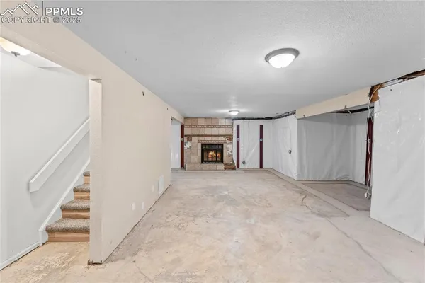 a view of an empty room with wooden floor and a ceiling fan