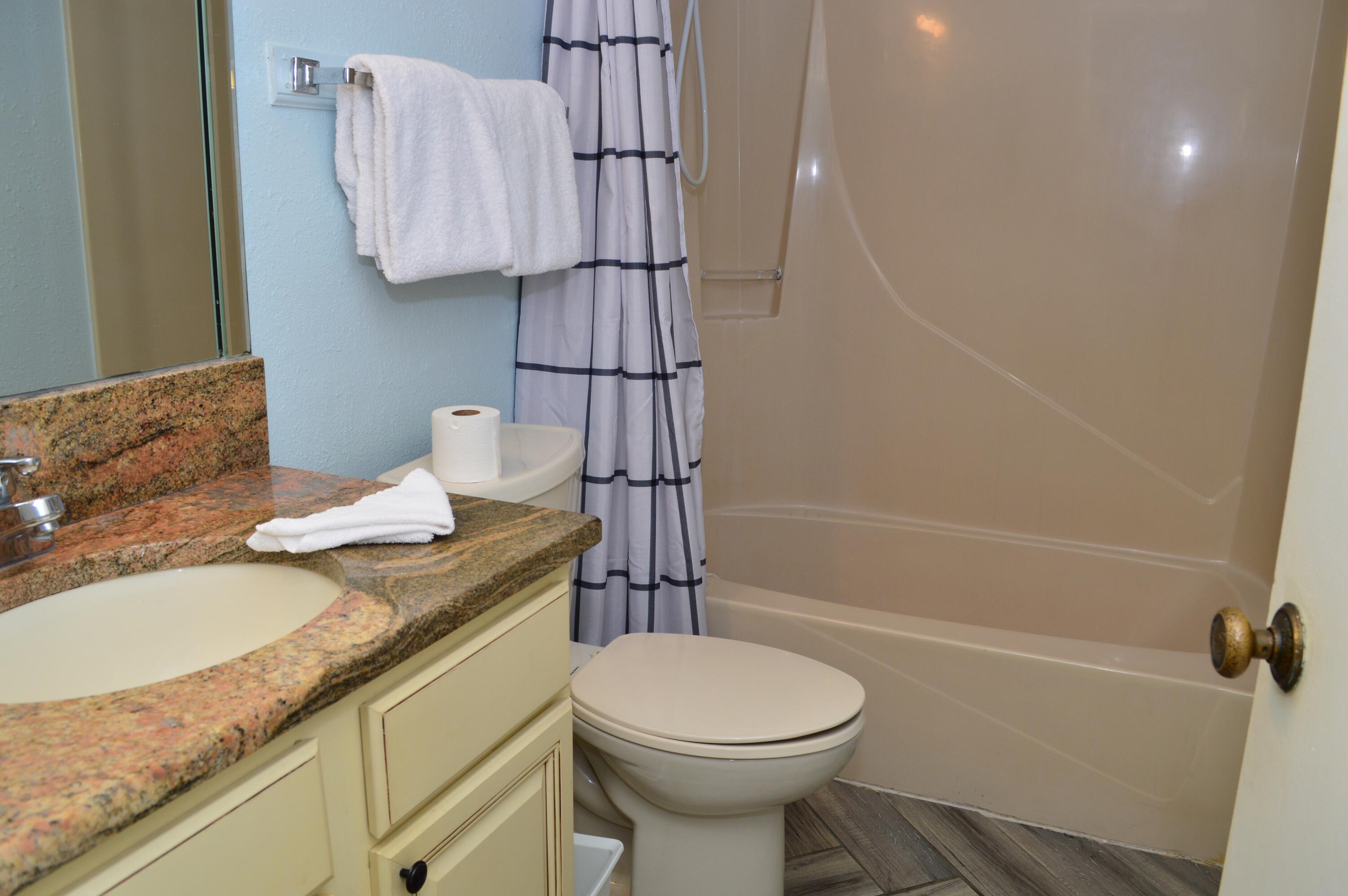 11483 Front Beach Road, Unit 307 Panama City Beach, FL 32407 - Photo 11 of 12 a bathroom with a granite countertop sink toilet and shower