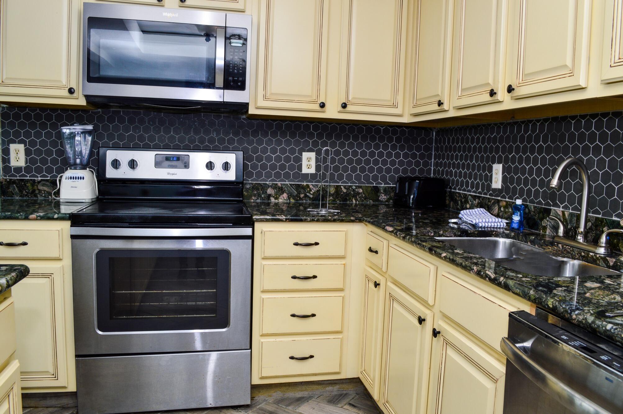11483 Front Beach Road, Unit 307 Panama City Beach, FL 32407 - Photo 3 of 12 a kitchen with granite countertop white cabinets and stainless steel appliances