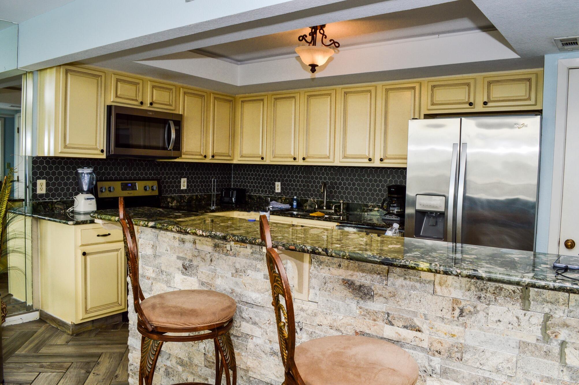 11483 Front Beach Road, Unit 307 Panama City Beach, FL 32407 - Photo 4 of 12 a kitchen with stainless steel appliances granite countertop a stove a sink and a refrigerator