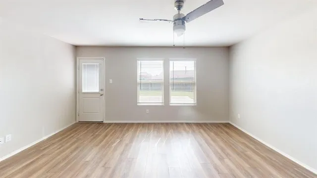 an empty room with wooden floor and windows
