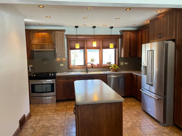 a kitchen with granite countertop a refrigerator a sink a stove and wooden cabinets