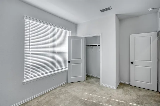 a view of an empty room with window and closet area