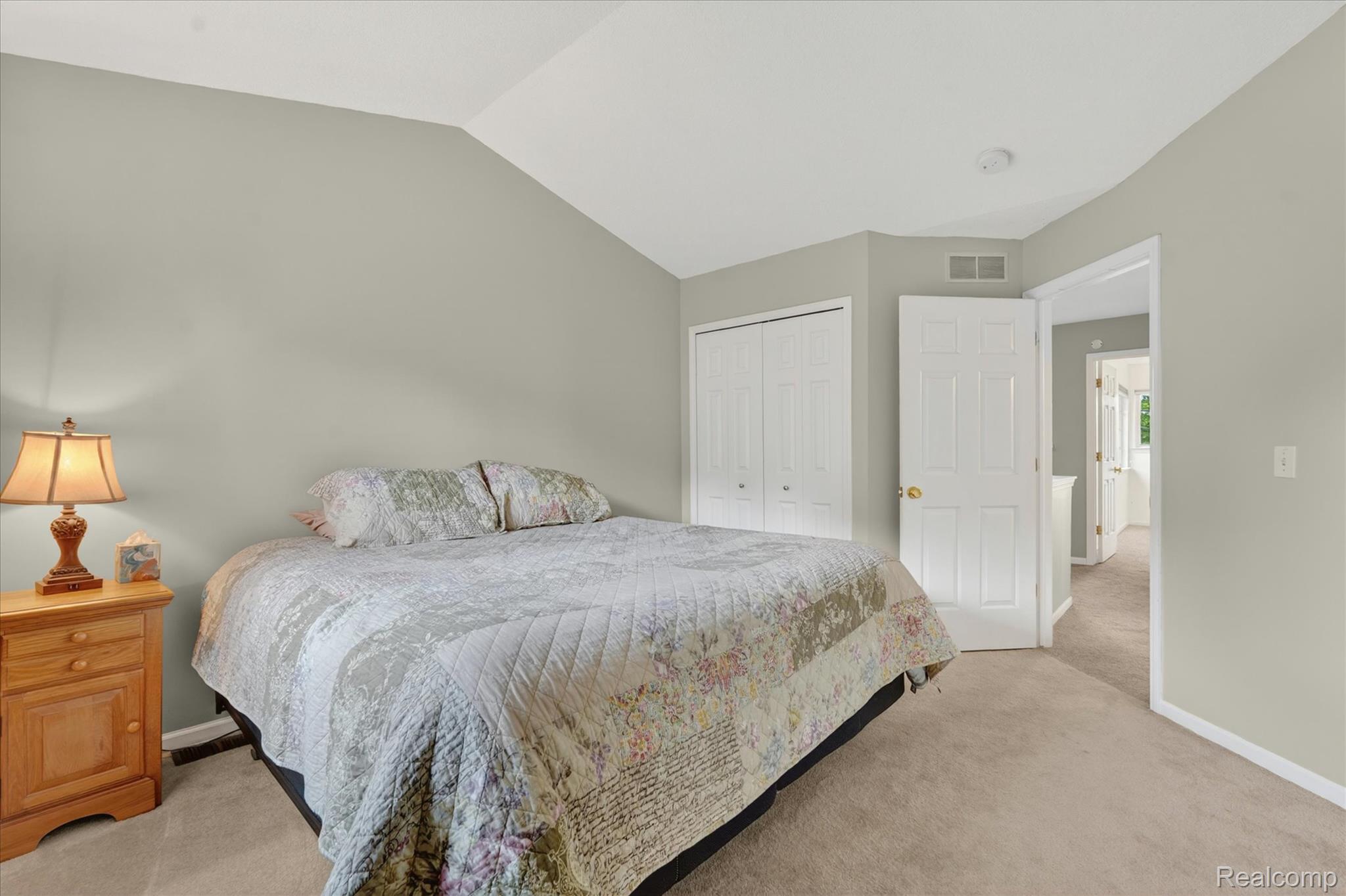 456 Lilly View Court Howell, MI 48843 - Photo 30 of 45 Vaulted ceiling bedroom with light gray walls, plush carpet flooring, a white paneled door, and a double bi-fold closet