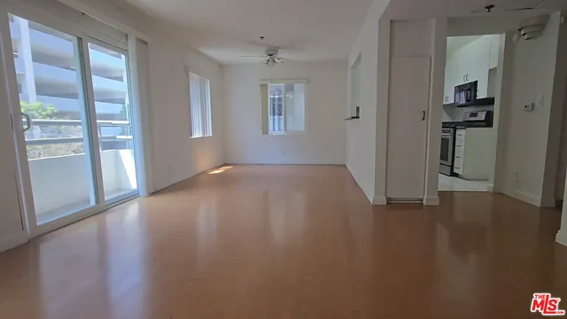 a view of an empty room with a window and wooden floor