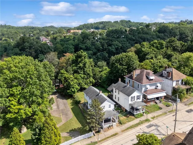 an aerial view of a residential houses with outdoor space and trees