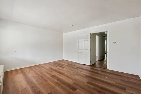 a view of an empty room with wooden floor and stairs