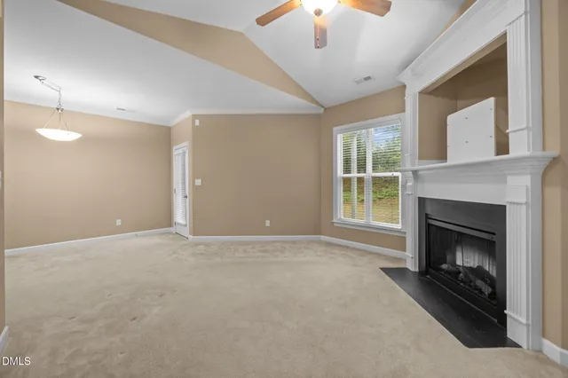 an empty room with windows fireplace and fan