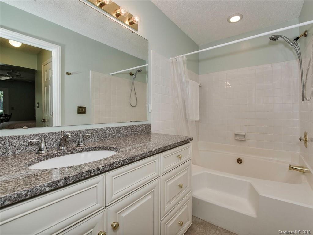 5009 Sharon Road Charlotte, NC 28210 - Photo 11 of 16 a bathroom with a granite countertop sink a mirror a bathtub and shower