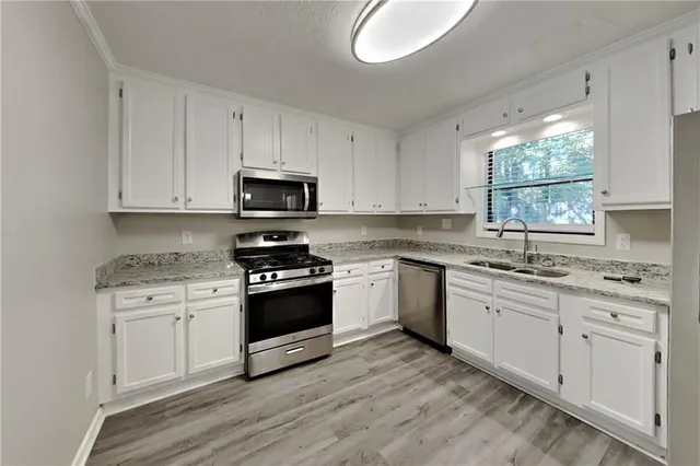 a kitchen with granite countertop white cabinets and a wooden floor