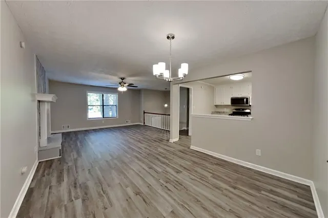 a view of a kitchen and an empty room with wooden floor and a window