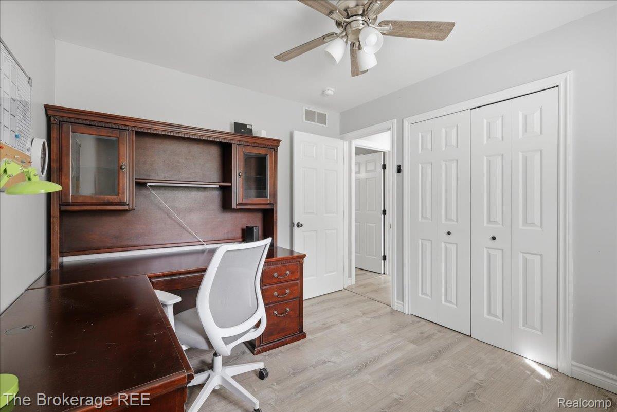 11282 Silver Lake Road Byron, MI 48418 - Photo 16 of 32 Light-toned wood-finish flooring, white paneled bifold closet doors, white paneled interior doors, and a ceiling fan with integrated lighting