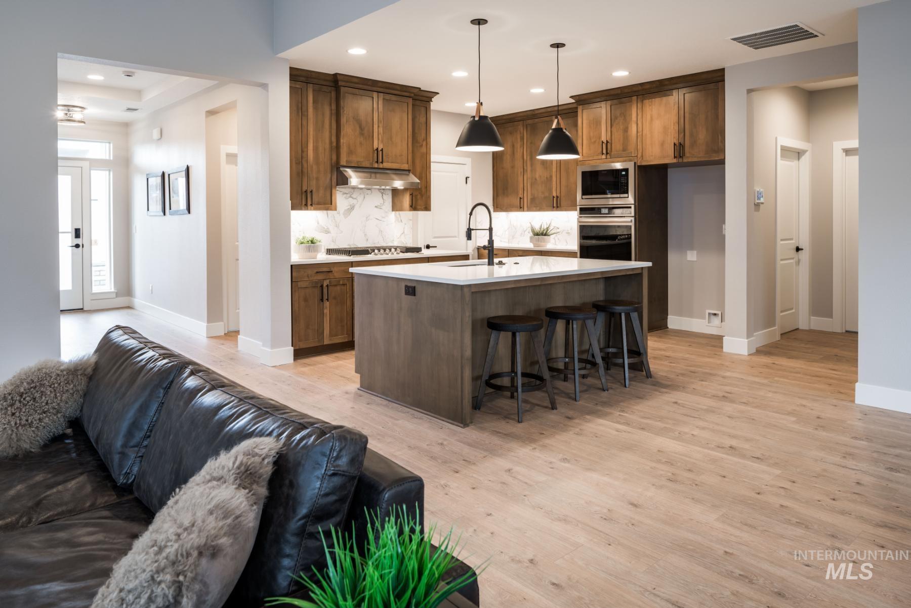 1279 West Malbar Street Meridian, ID 83646 - Photo 23 of 23 Kitchen with open floor plan, backsplash, light wood-style floors, a kitchen bar, and light countertops