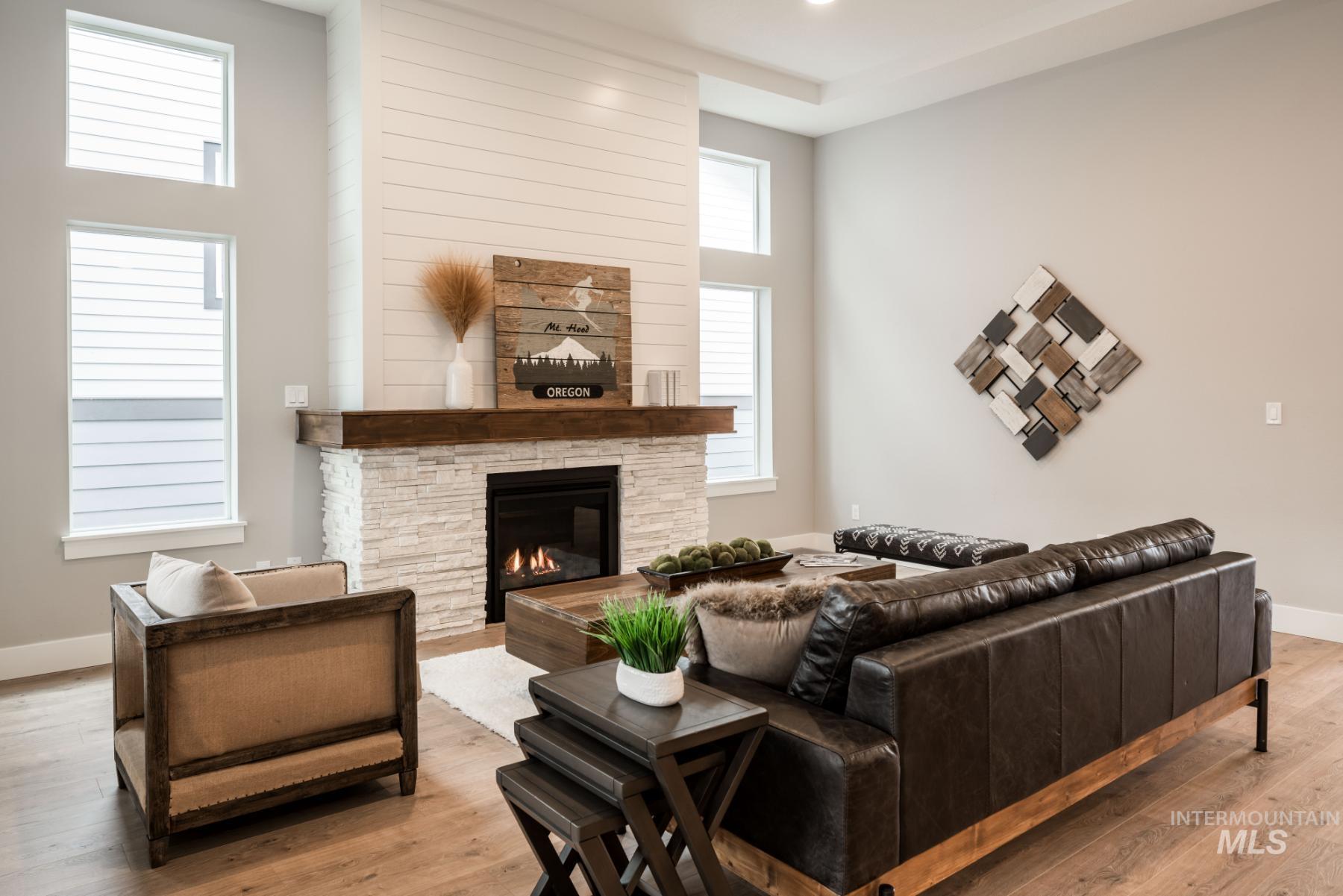 1279 West Malbar Street Meridian, ID 83646 - Photo 13 of 23 Living area featuring wood finished floors, a stone fireplace, and a high ceiling