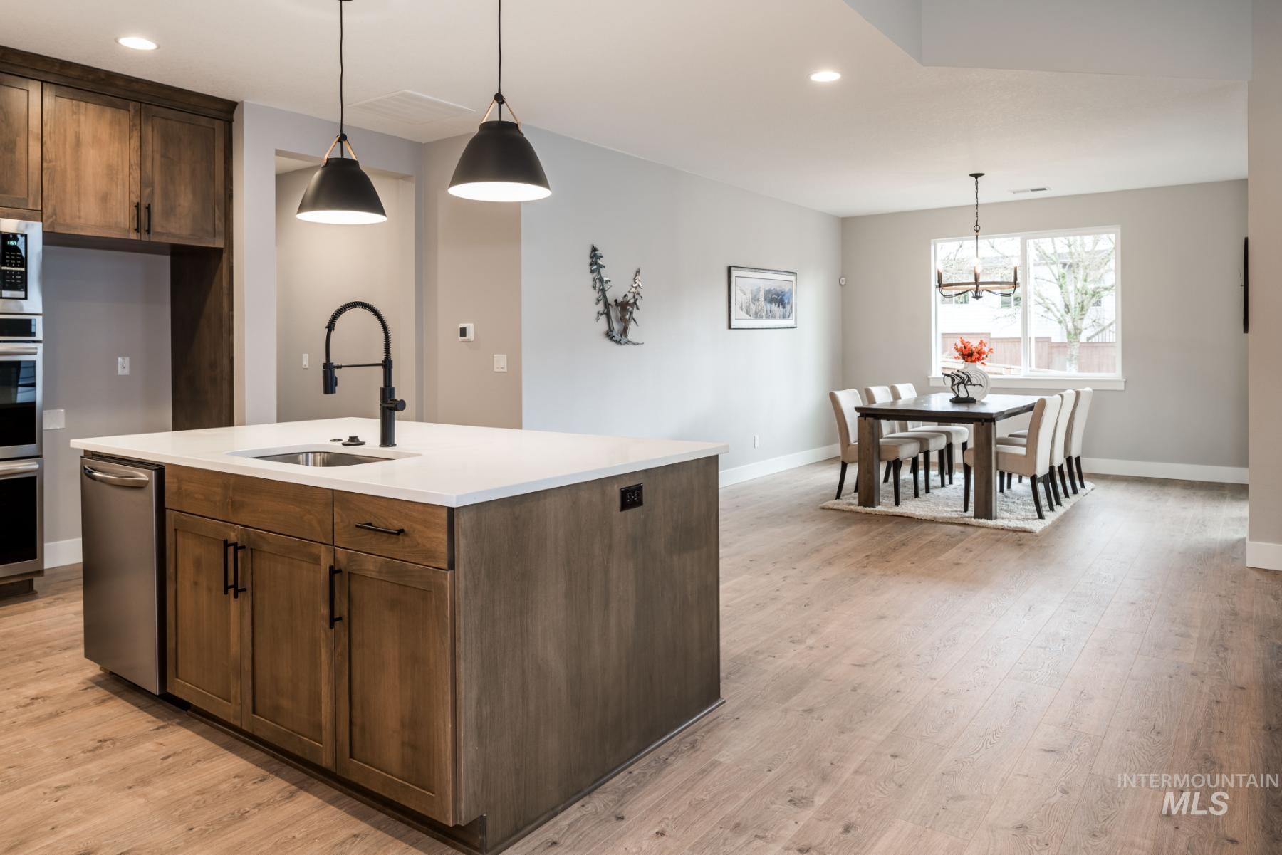 1279 West Malbar Street Meridian, ID 83646 - Photo 4 of 23 Kitchen featuring recessed lighting, light wood-style flooring, pendant lighting, light countertops, and appliances with stainless steel finishes
