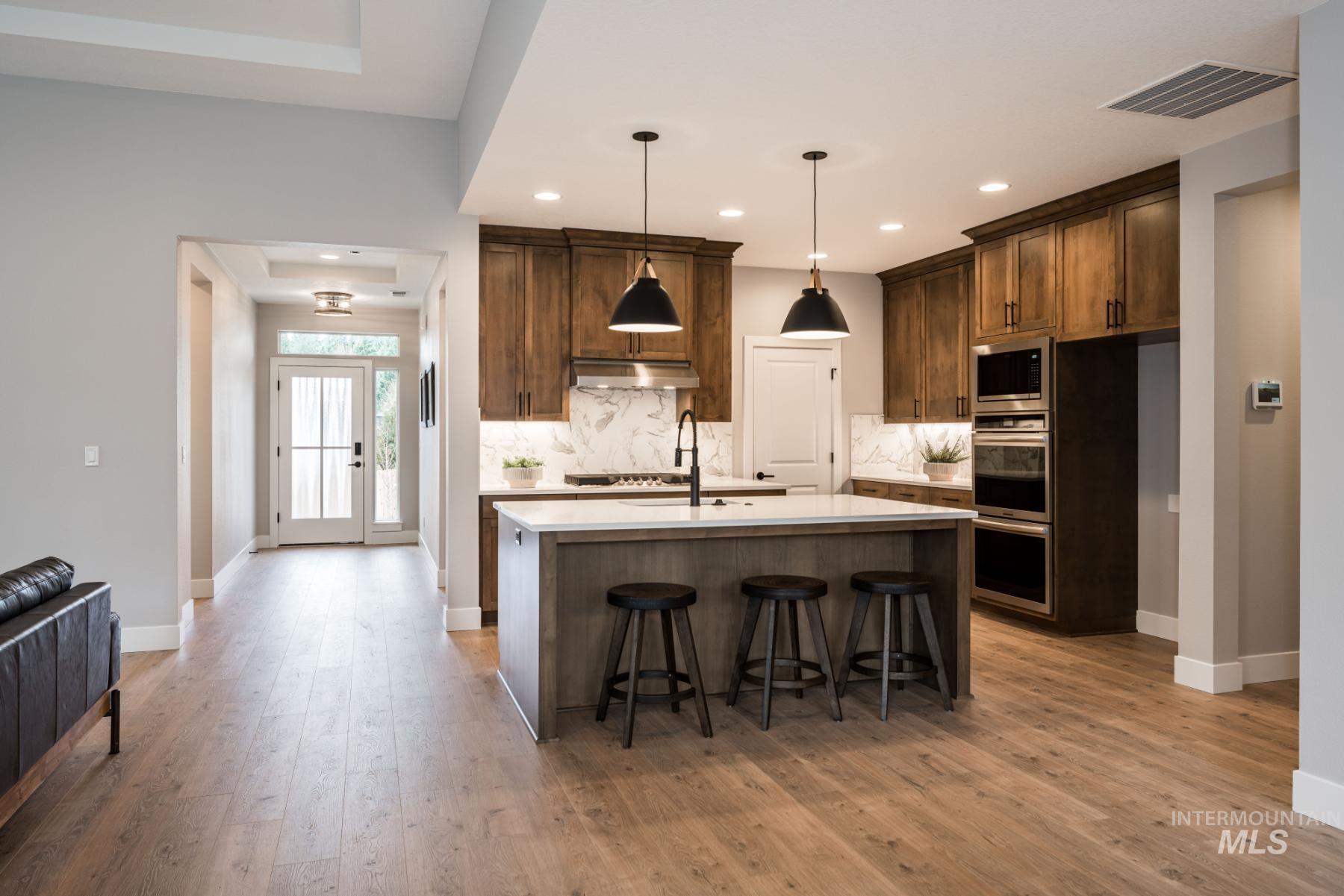 1279 West Malbar Street Meridian, ID 83646 - Photo 8 of 23 Kitchen with backsplash, light countertops, a kitchen island with sink, light wood finished floors, and recessed lighting