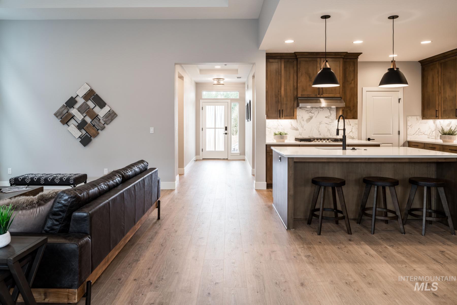 1279 West Malbar Street Meridian, ID 83646 - Photo 22 of 23 Kitchen with light countertops, decorative backsplash, light wood finished floors, a breakfast bar area, and open floor plan