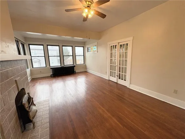 an empty room with windows fireplace and wooden floor