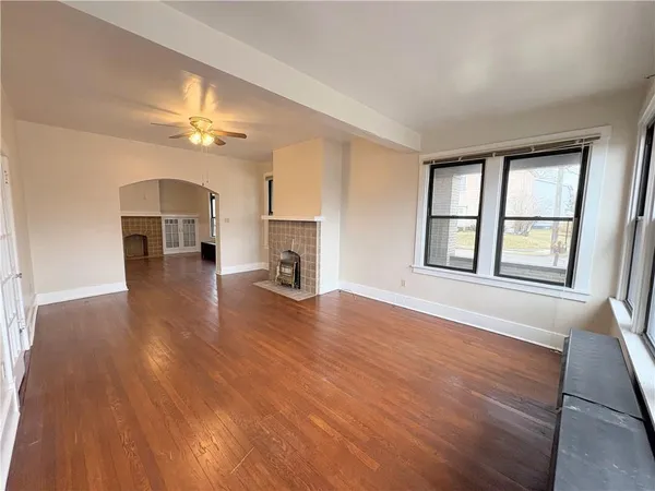 an empty room with wooden floor fireplace and windows