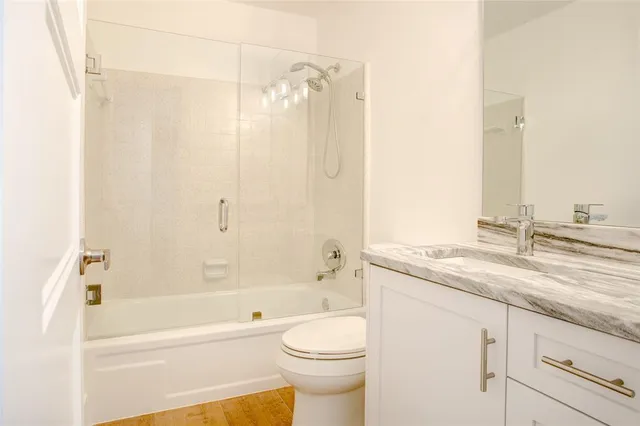 a bathroom with a granite countertop sink a toilet and shower