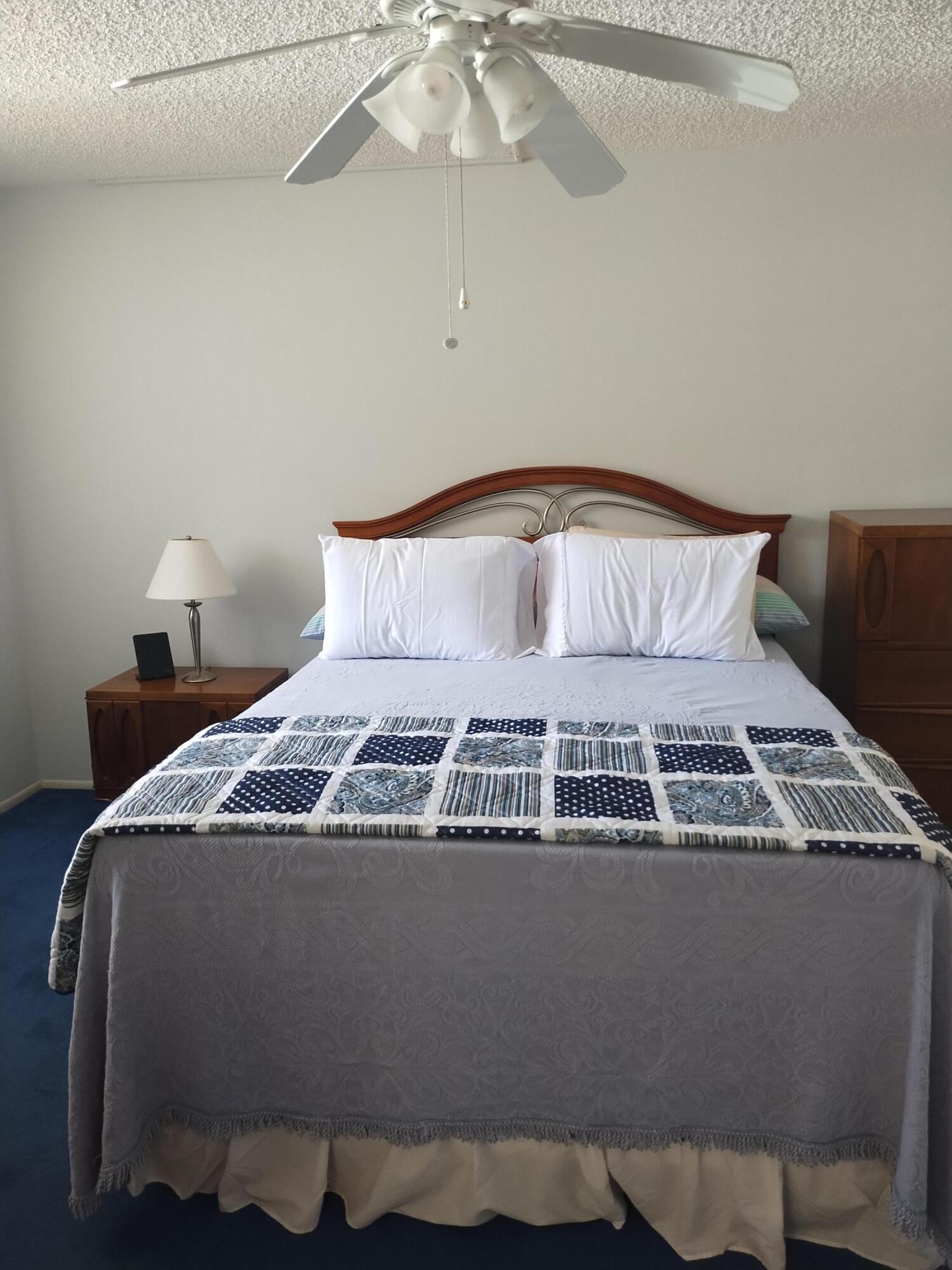 6461 Northwest 2nd Avenue, Unit 102 Boca Raton, FL 33487 - Photo 13 of 30 a bedroom with a bed and chandelier